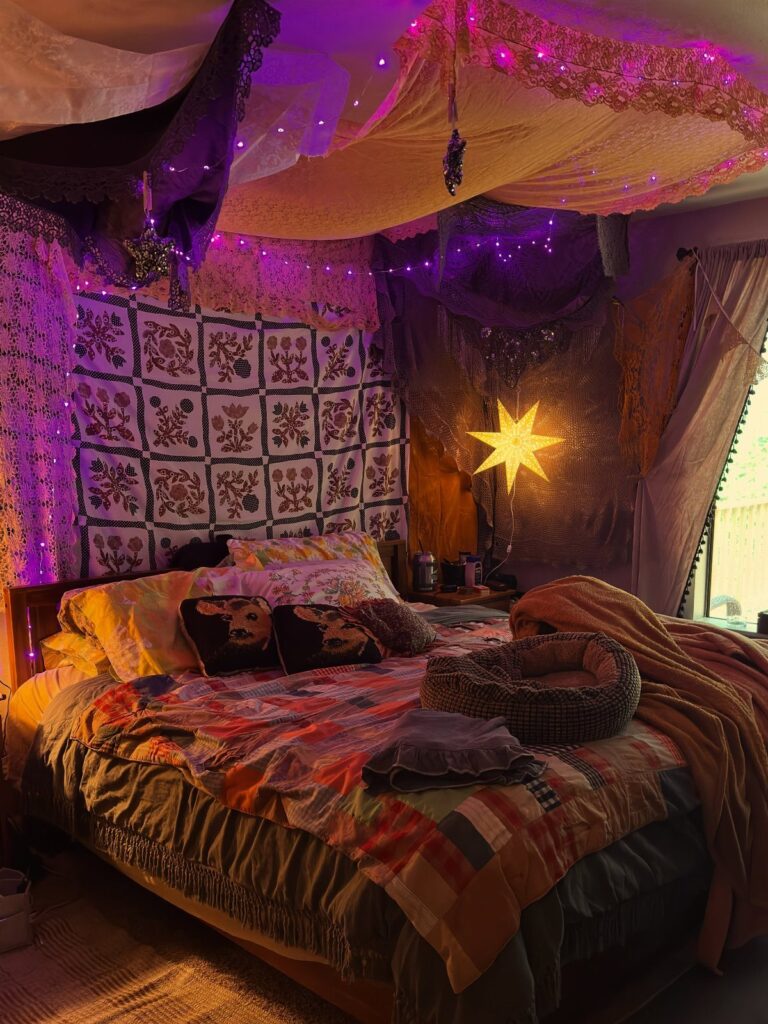 Bed with patchwork quilt and brown throw under purple string lights and canopies