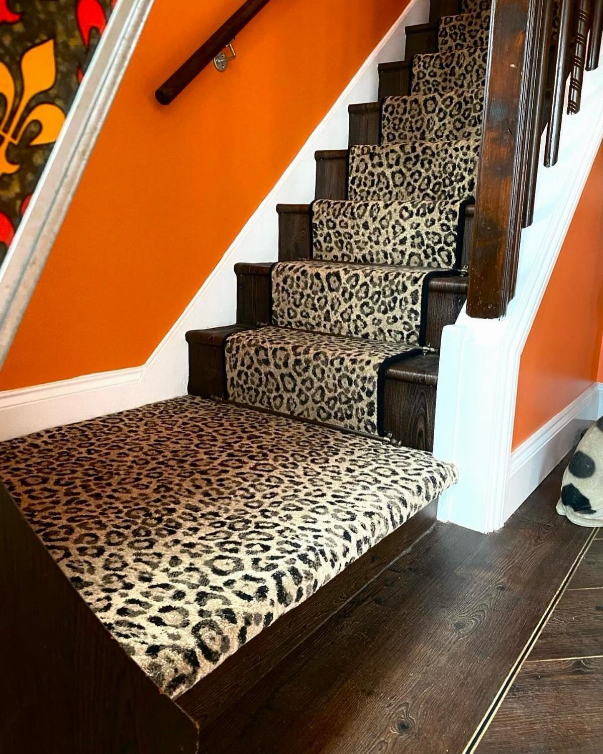 Stairs with Carpet: 23 Styles from Runners to Bold Patterns 19 Leopard-print carpet runner on wooden stairs against a bright orange wall