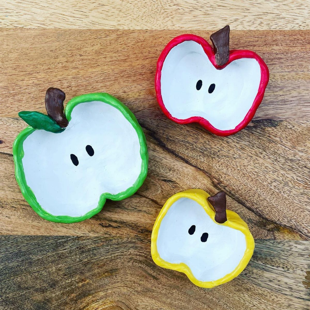 30 DIY Clay Crafts to Make with Air-Dry Clay for Home Decor 12 Three apple-shaped clay pinch pots in red, green, and yellow on a wooden table.