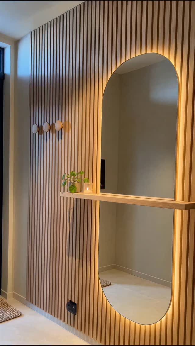 Mirror Wall Art: 25 Ideas from Sunburst to Floor Mirrors 5 Arched backlit mirror recessed into a vertical light-wood slat wall with a small shelf.