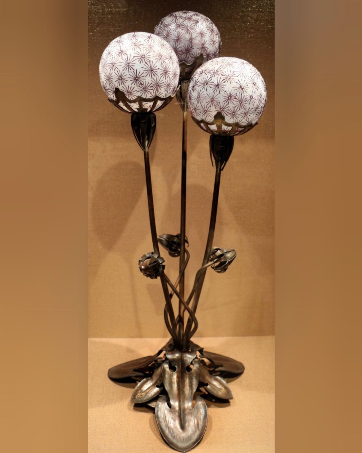 Wrought iron flower lamp with three spherical white glass floral shades and dark stems.