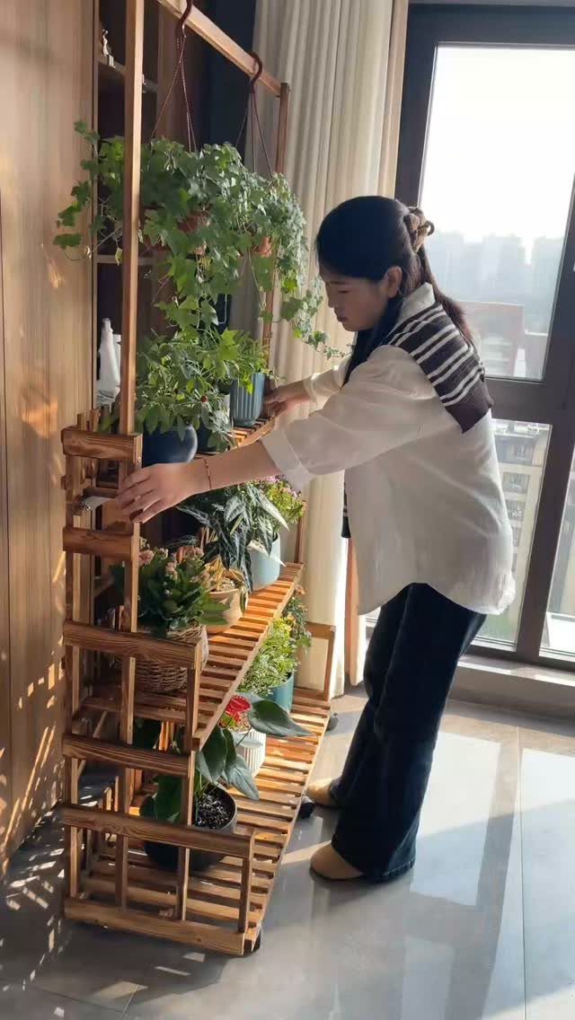 38 Flower Pot on Stand Ideas, from Iron Frames to Pedestals 17 Bamboo slat plant stand with multiple tiers holding various potted green indoor plants.