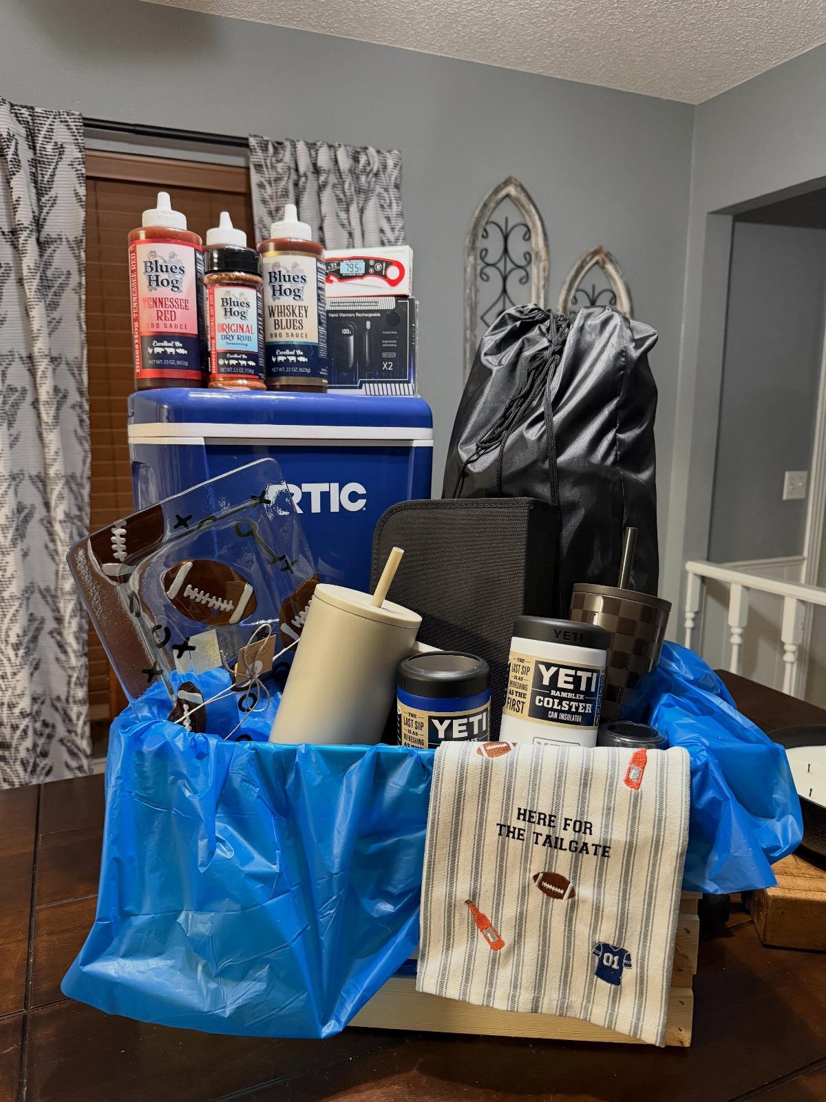 BBQ gift basket with sauces, Yeti gear, and a blue cooler for tailgating.