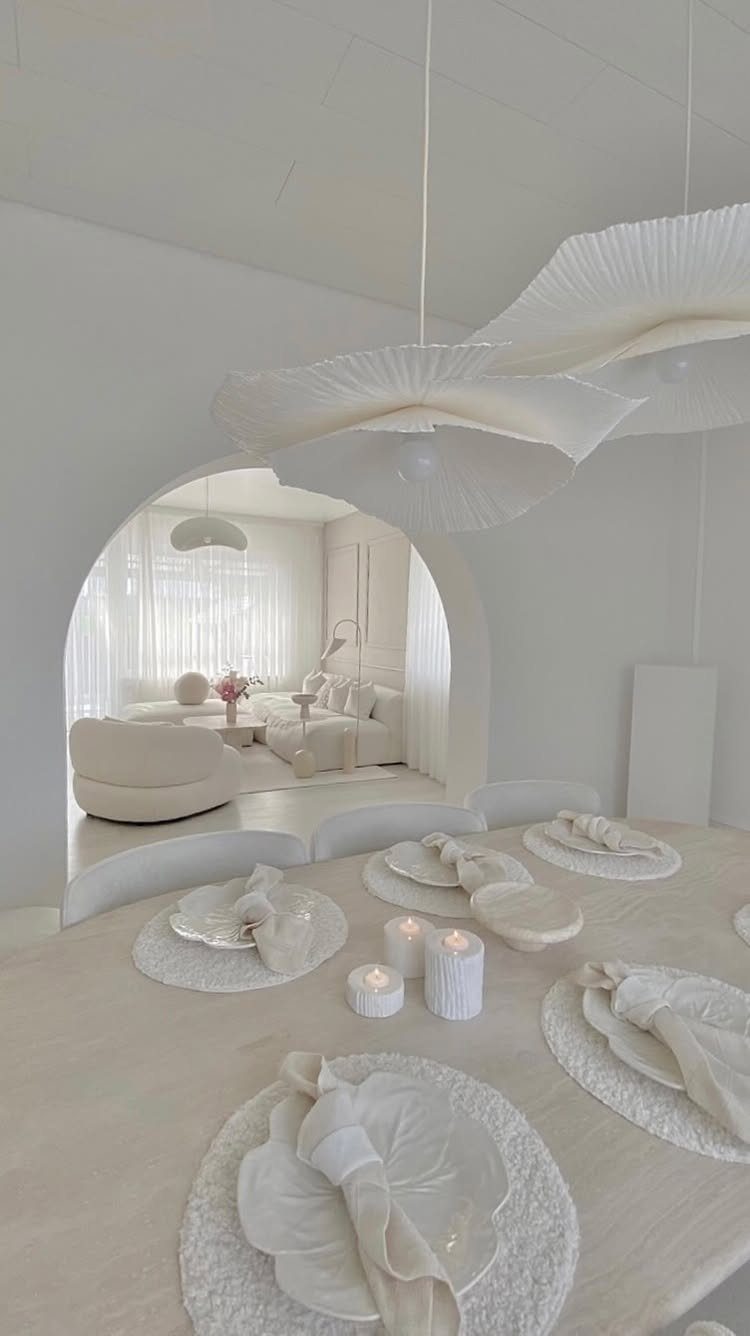 Monochromatic white and beige dining room with a set table and arched living area.