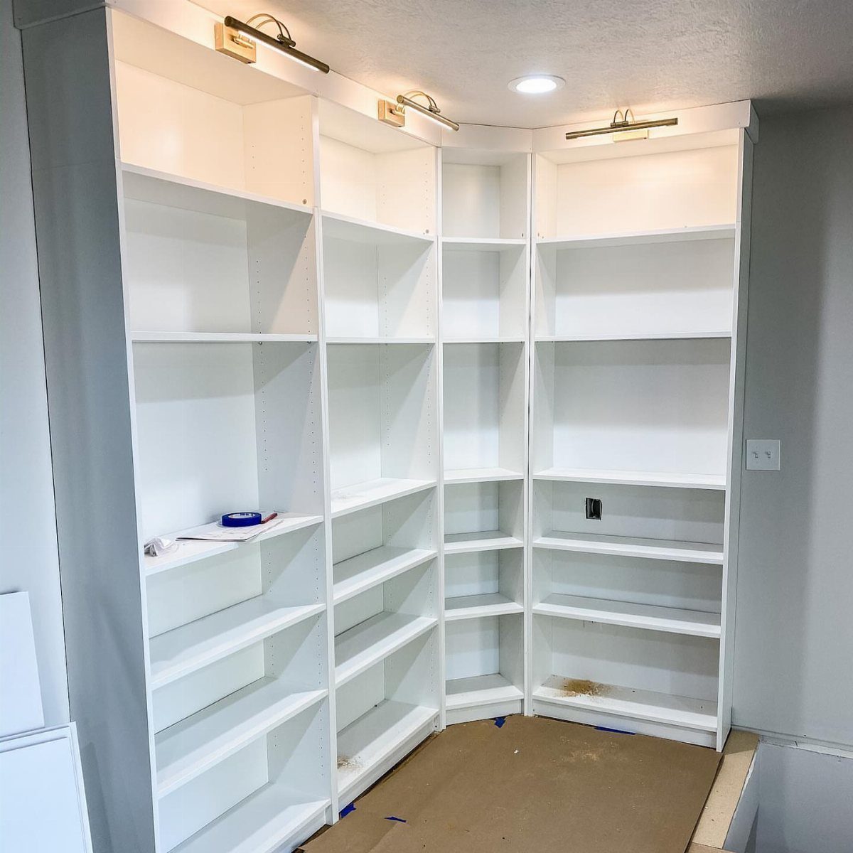 24 Corner Shelves IKEA Ideas for Kitchens, TVs and Plants 2 White built-in corner bookcases with gold lighting and empty shelves in a room.
