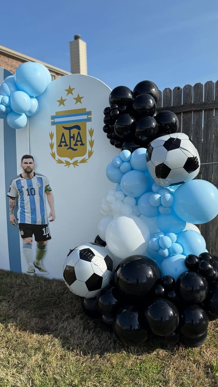 Man in soccer jersey posing by AFA backdrop and soccer-themed balloon arrangement.