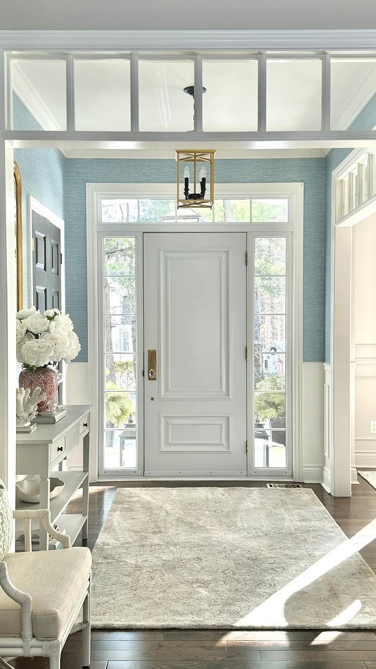 14 Home Decor Blue Ideas for Sofas, Walls, Kitchens and Baths 6 Light blue entryway with white front door, neutral rug, and white console table.