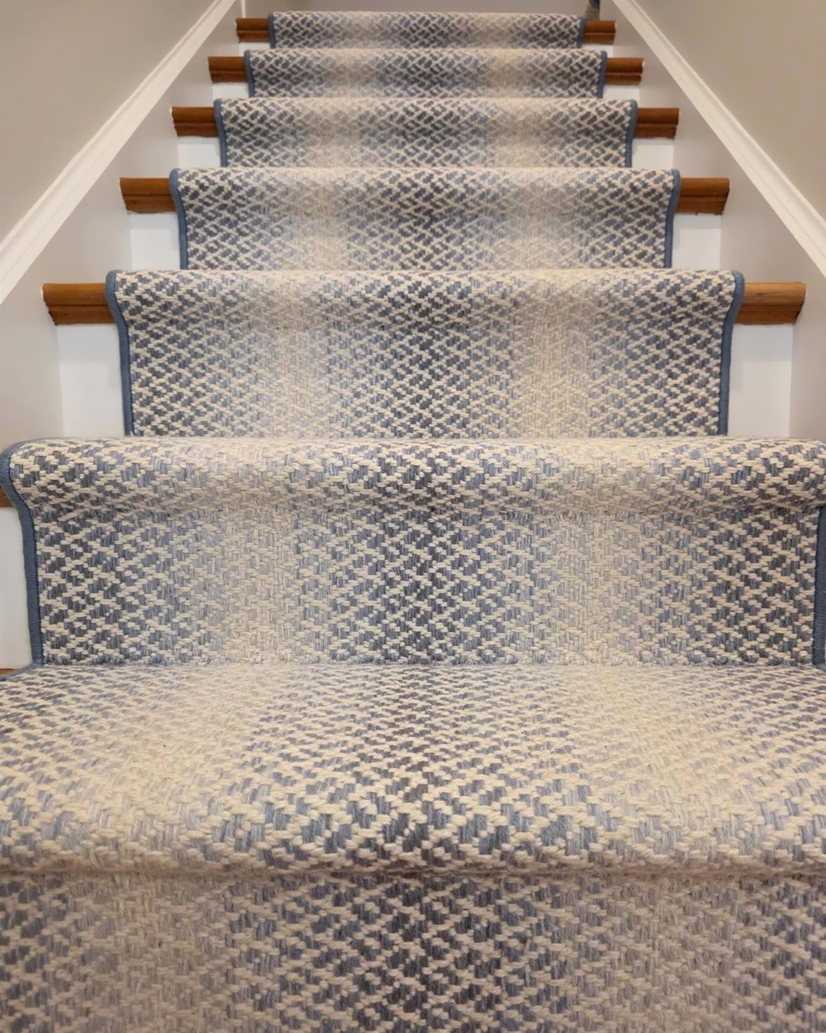 Stairs with Carpet: 23 Styles from Runners to Bold Patterns 17 Blue and cream patterned carpet runner on a wooden staircase with white walls.