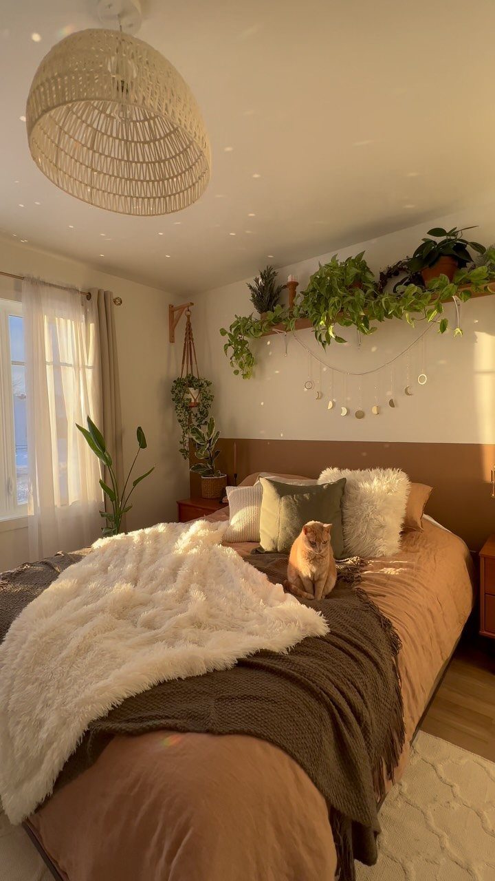 Cozy bedroom with layered textures, woven light fixture, and trailing indoor plants.