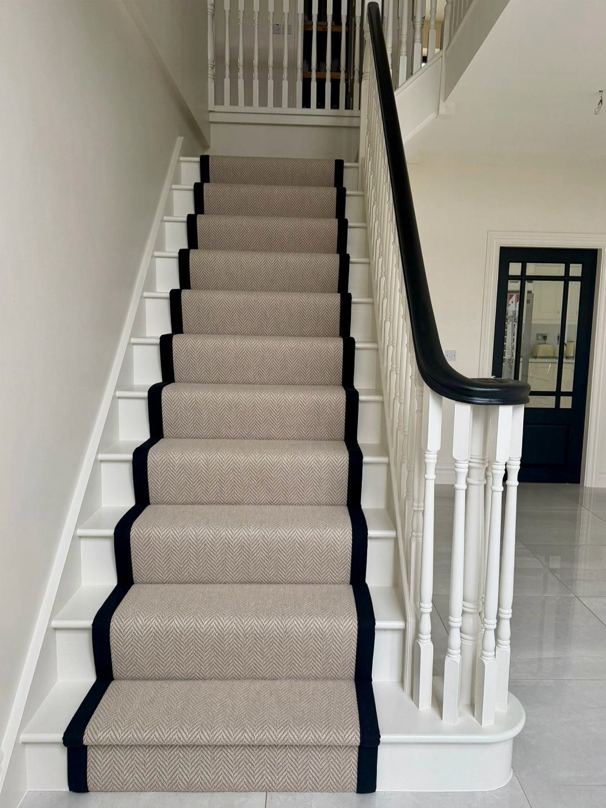 Stairs with Carpet: 23 Styles from Runners to Bold Patterns 15 Beige textured carpet runner with black borders on white wooden stairs with black railing.