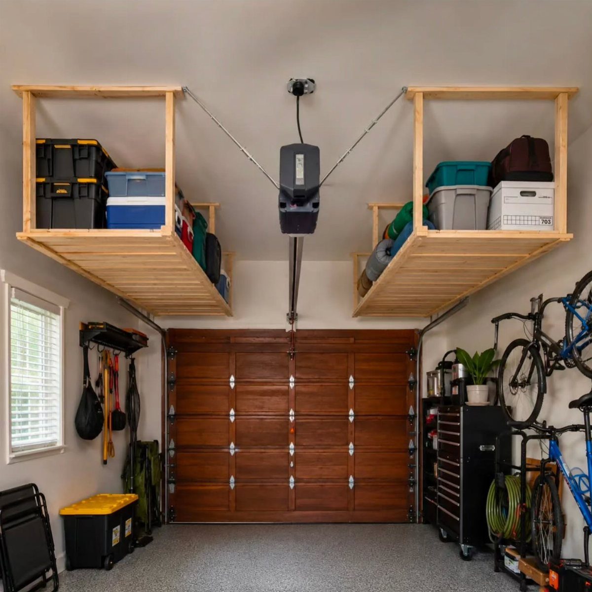 Wooden ceiling-mounted storage shelves in a garage holding various plastic storage bins.