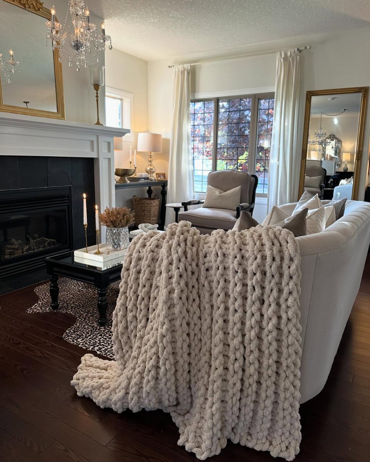 Cream chunky knit throw draped over a white sofa in a cozy living room.