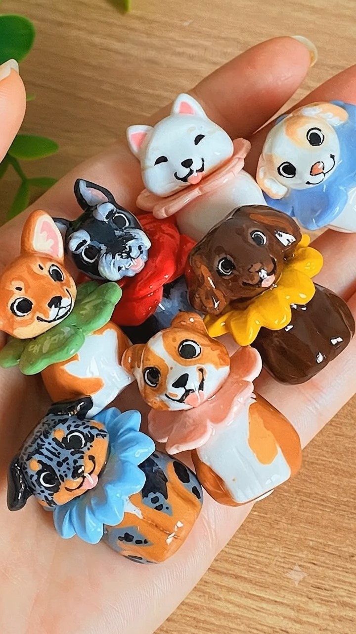 30 DIY Clay Crafts to Make with Air-Dry Clay for Home Decor 17 Small colorful sculpted clay animal figures with ruffled collars held in a hand.