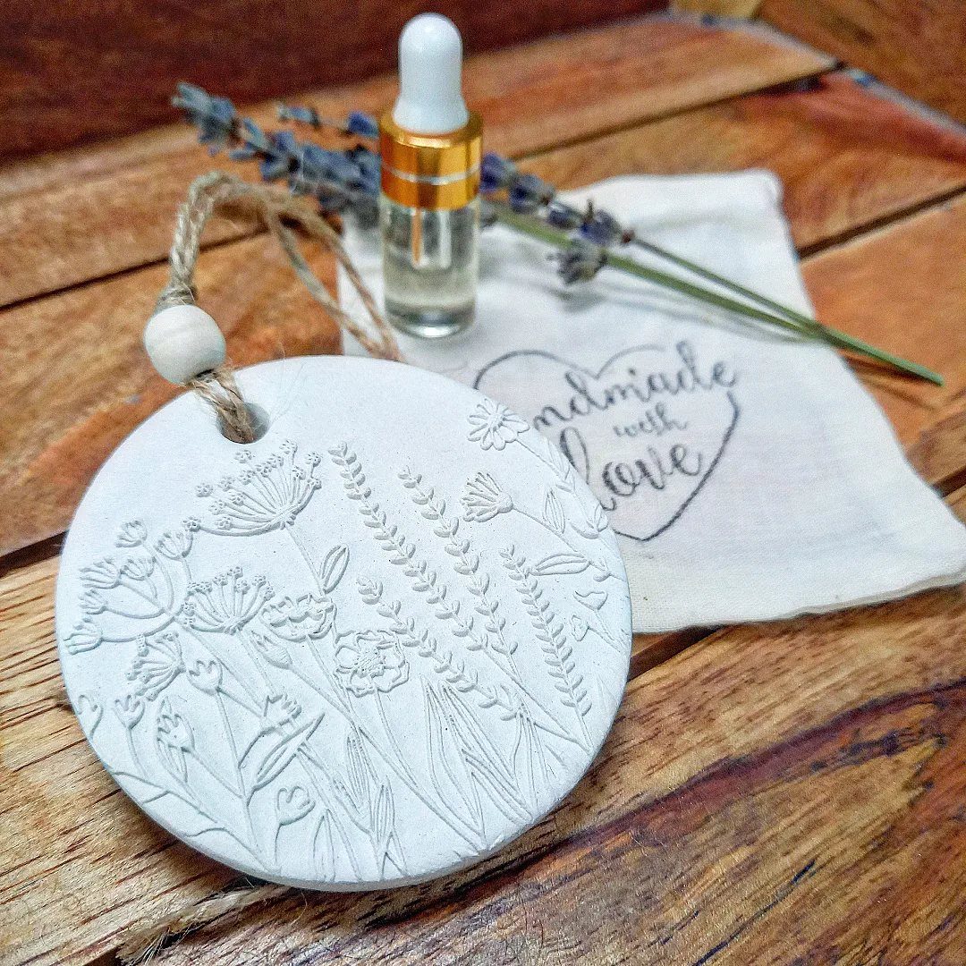 30 DIY Clay Crafts to Make with Air-Dry Clay for Home Decor 18 White embossed clay diffuser disc with essential oil bottle and lavender on wood.