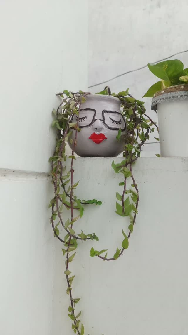 30 DIY Clay Crafts to Make with Air-Dry Clay for Home Decor 24 Face-shaped grey clay pot with glasses and red lips holding a trailing plant.