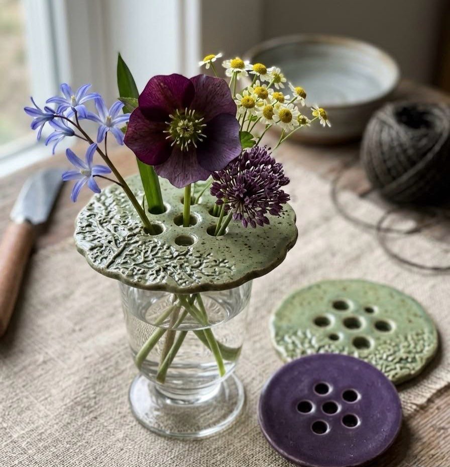 30 DIY Clay Crafts to Make with Air-Dry Clay for Home Decor 19 Perforated clay flower frogs holding a bouquet of purple and yellow flowers in a vase.