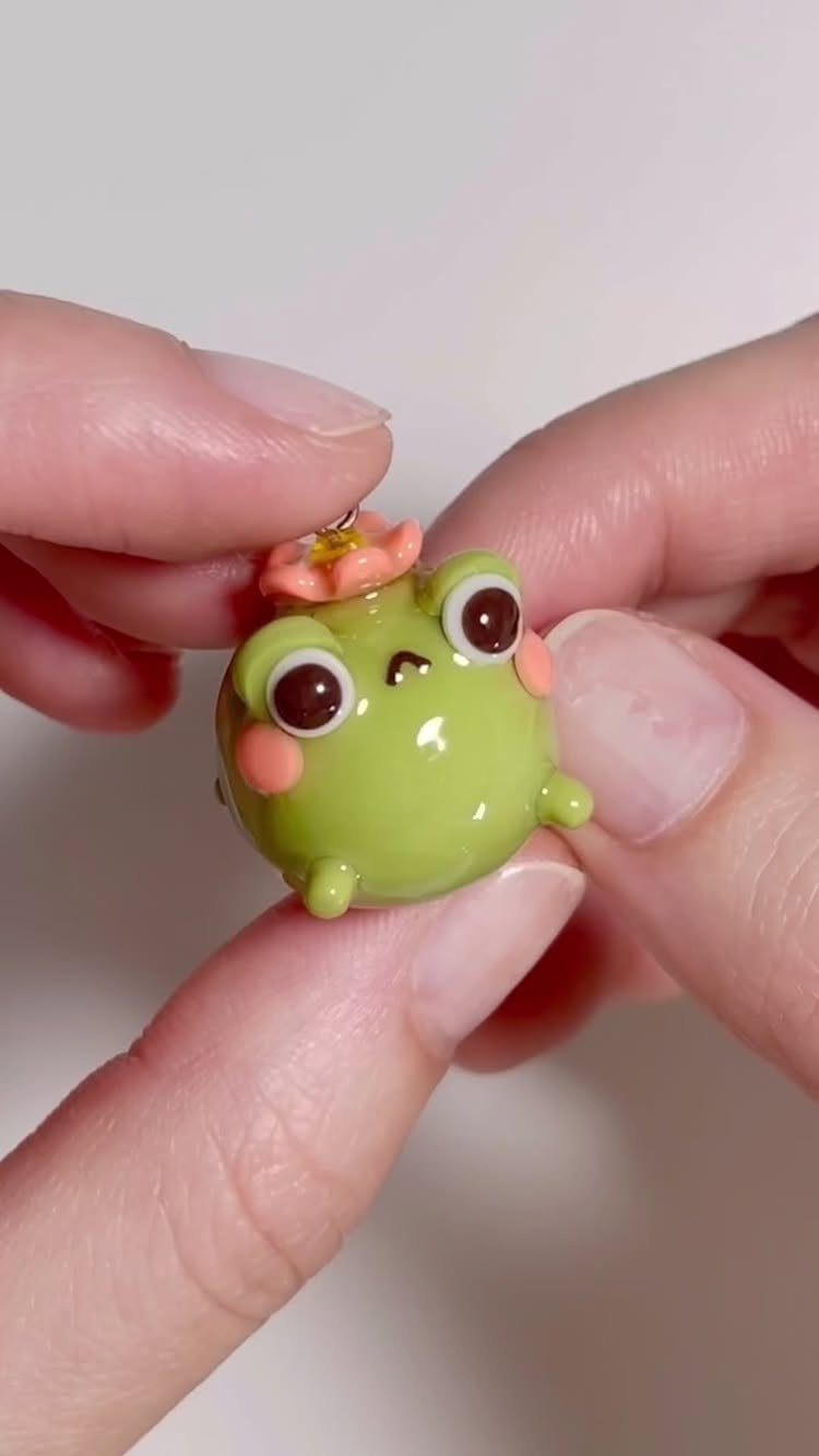 30 DIY Clay Crafts to Make with Air-Dry Clay for Home Decor 25 Small glossy green clay frog figurine with a tiny flower on its head.