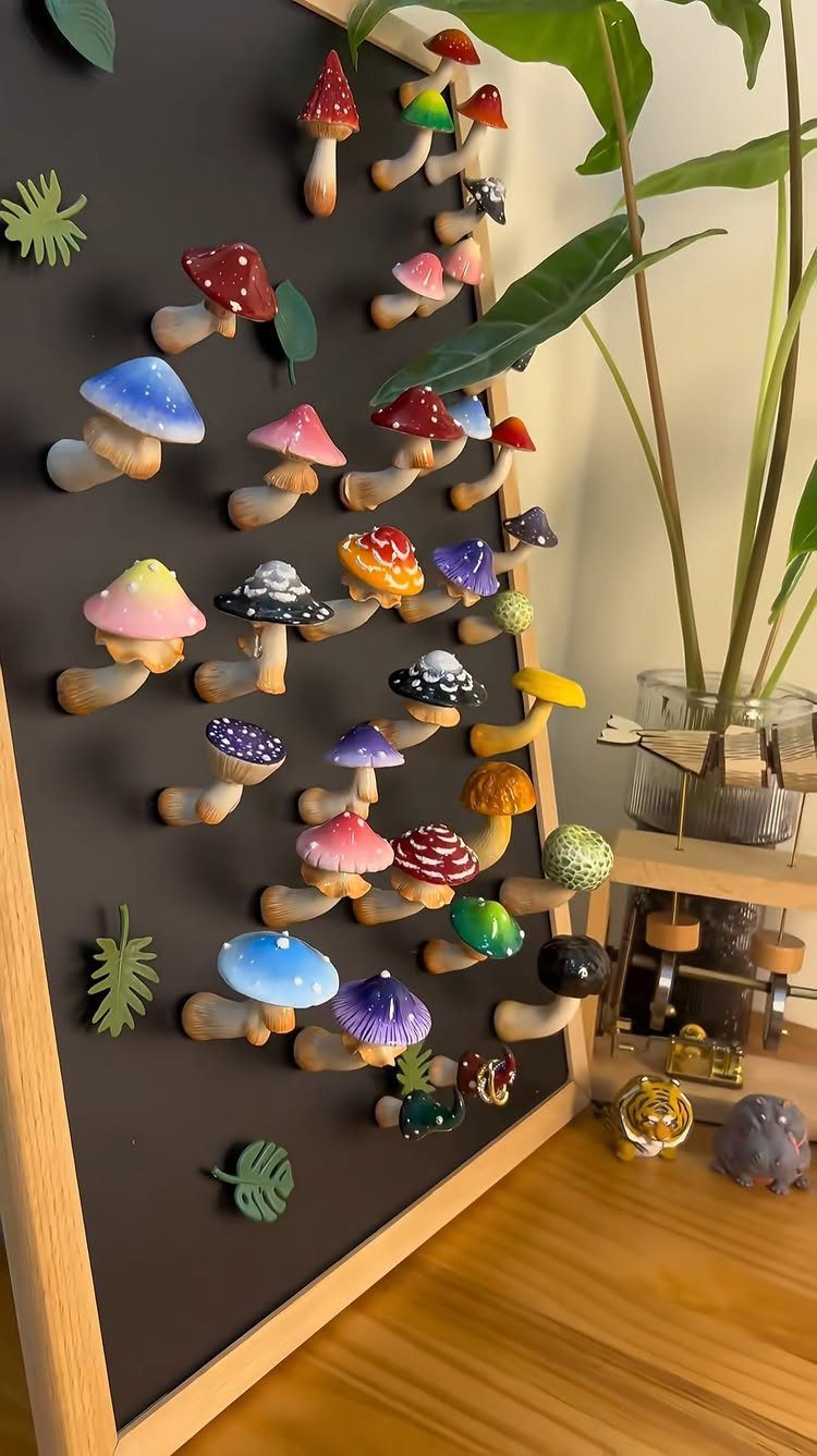 30 DIY Clay Crafts to Make with Air-Dry Clay for Home Decor 9 Colorful clay mushrooms and green leaves attached to a black framed board.
