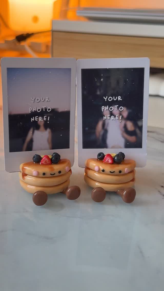 30 DIY Clay Crafts to Make with Air-Dry Clay for Home Decor 13 Pancake-shaped clay photo holders supporting two polaroid photographs on a white table.