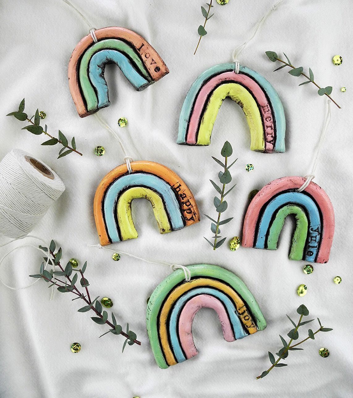 30 DIY Clay Crafts to Make with Air-Dry Clay for Home Decor 15 Five colorful handmade clay rainbows with pastel stripes on a white fabric background.