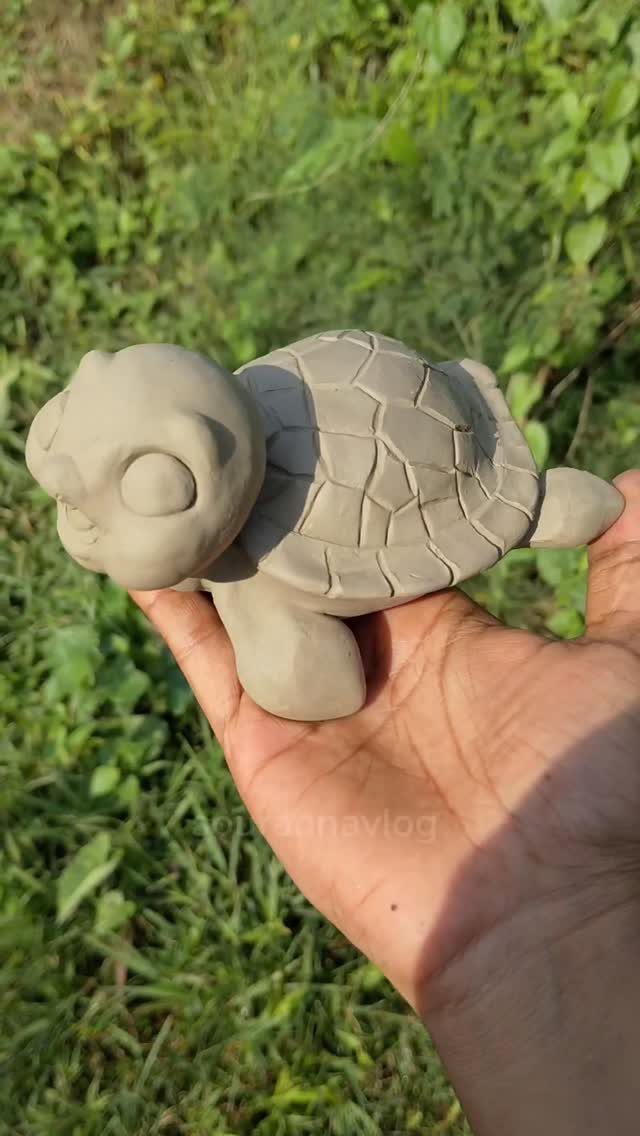 30 DIY Clay Crafts to Make with Air-Dry Clay for Home Decor 26 Small grey clay turtle sculpture held in a hand against a grassy background.