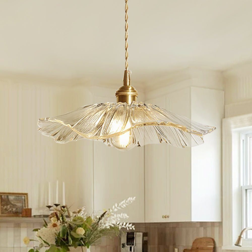 Clear glass flower shaped pendant lamp hanging in a bright white kitchen.