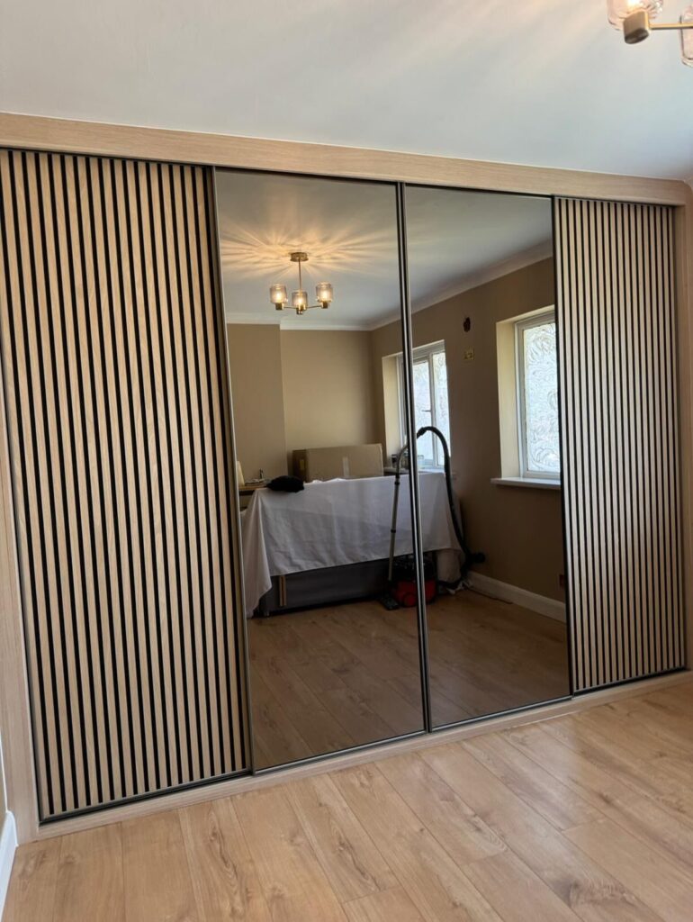Sliding closet doors with central mirrored panels and outer vertical wood slat panels.