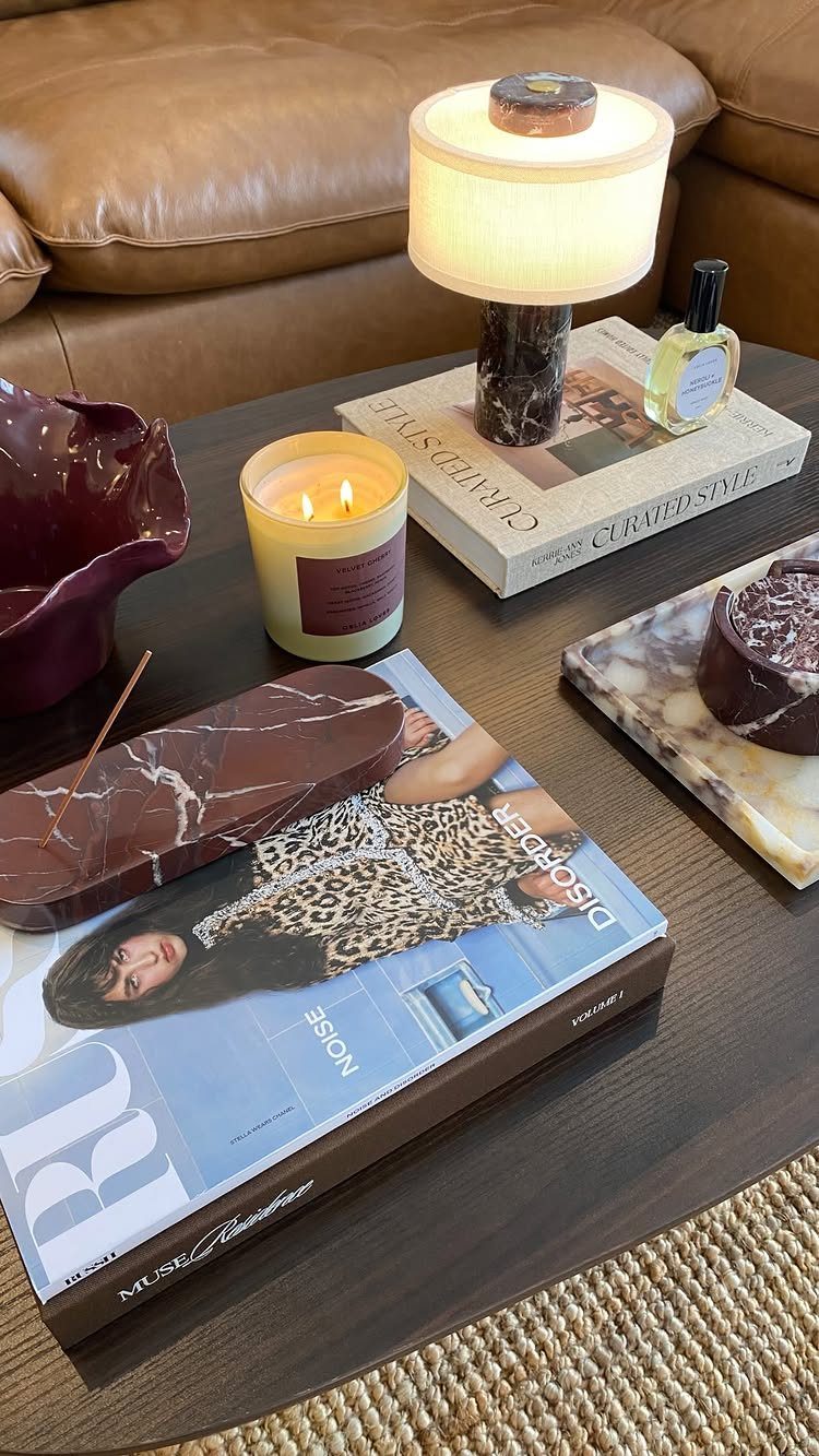 40 Home Decor Item Ideas, From Candle Holders to Sculptures 33 Dark brown coffee table with a lamp, candle, and magazine in a living room.