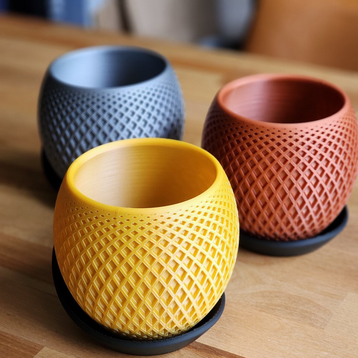 House Plant Pots: 21 Ideas in Ceramic, Terracotta and Metal 5 Three colorful geometric plant pots in yellow, orange, and grey on a wooden table.