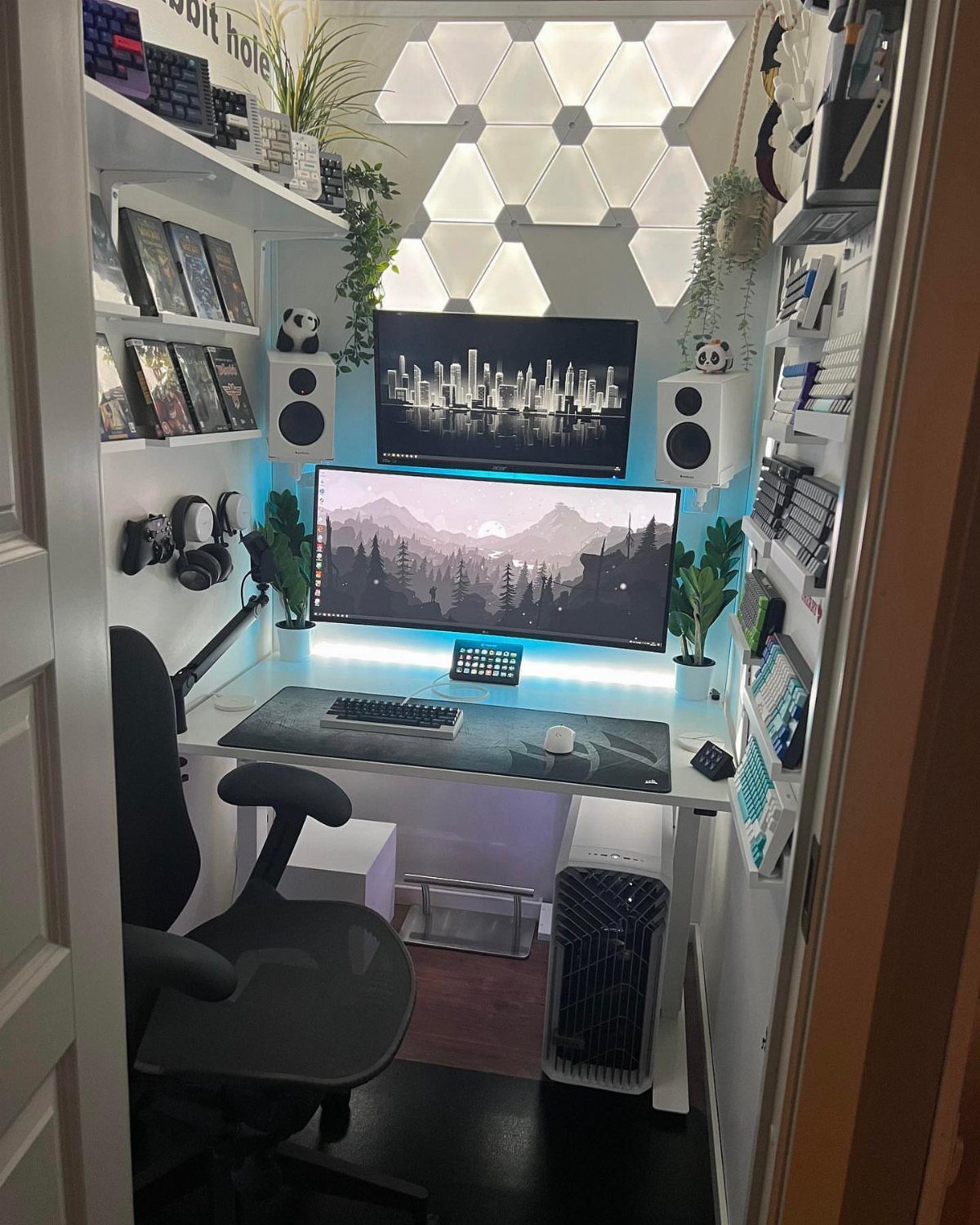 13 Alt Room Decor Ideas with Moody Colors, Wood, and Plants 7 Compact white hobby desk with dual monitors, hexagonal wall lights, and gaming accessories.