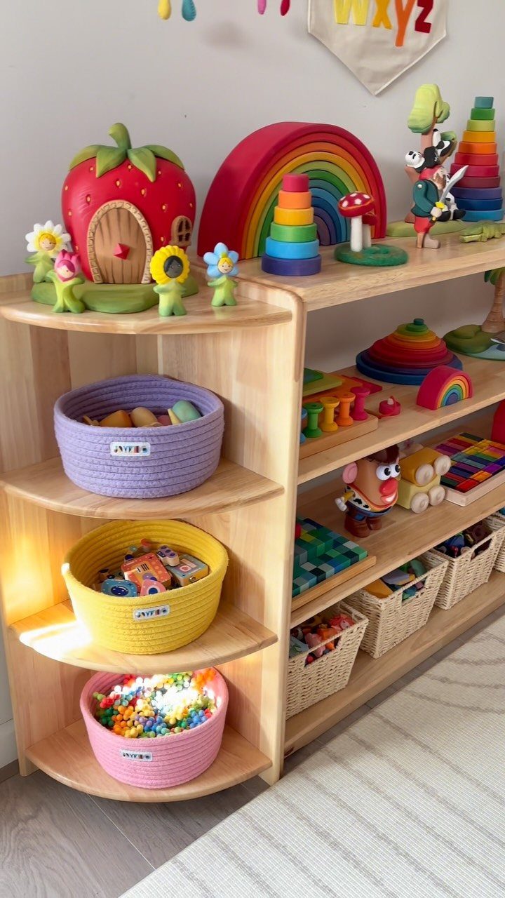 Curved wooden corner shelves holding colorful woven baskets filled with children's toys.