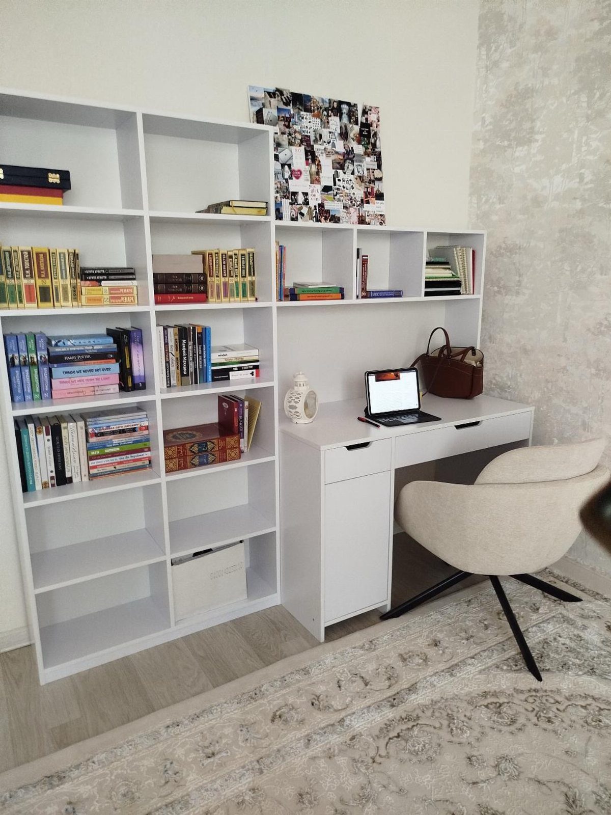 White desk with laptop and chair next to a large white bookshelf.