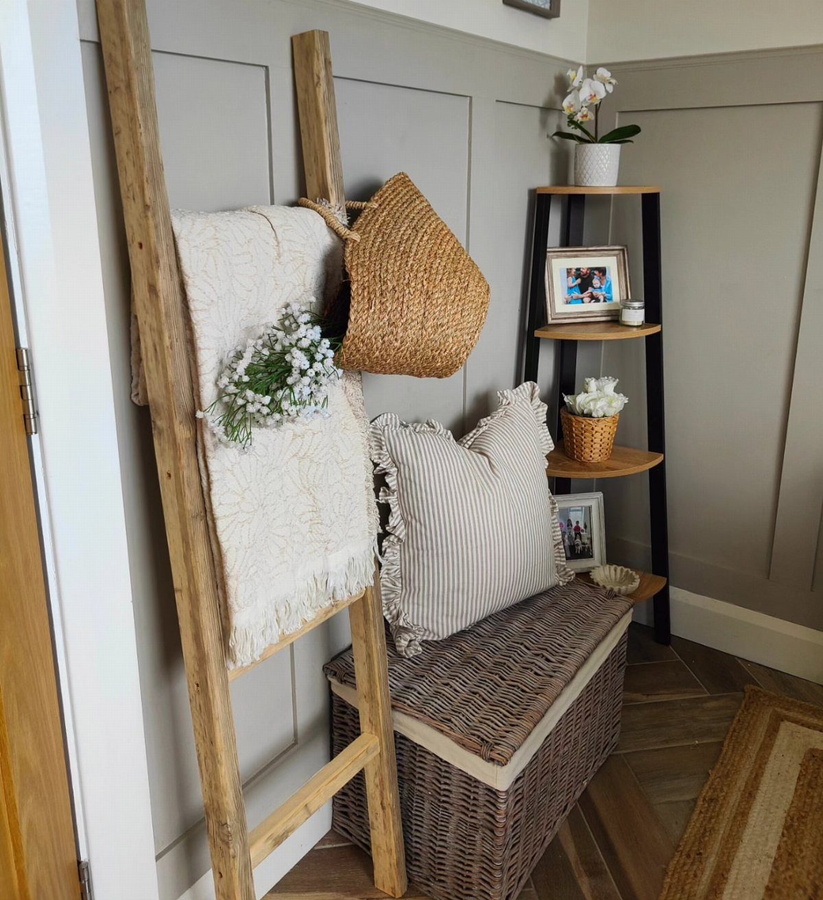Wooden decorative ladder with a blanket and basket in a living room corner.