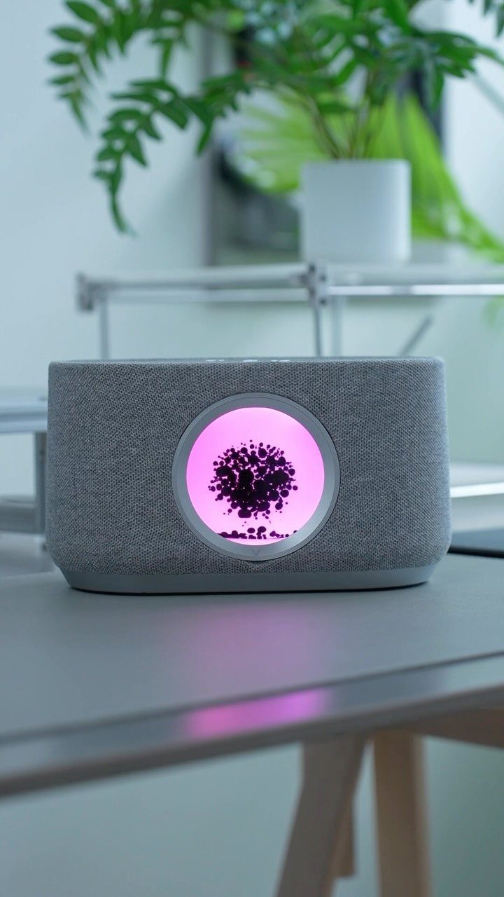 23 Cool House Items for Walls, Shelves, Desks, and Baths 19 Grey smart speaker with a glowing pink circular display on a grey table.