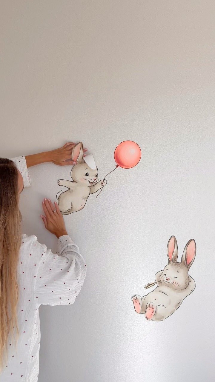 Person applying cute bunny rabbit wall decals with a red balloon to a wall