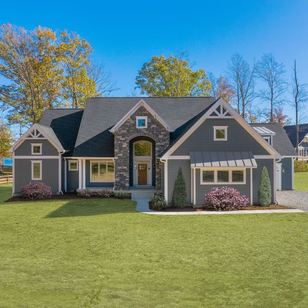 Grey house with a dark roof and a central arched stone portico entrance.
