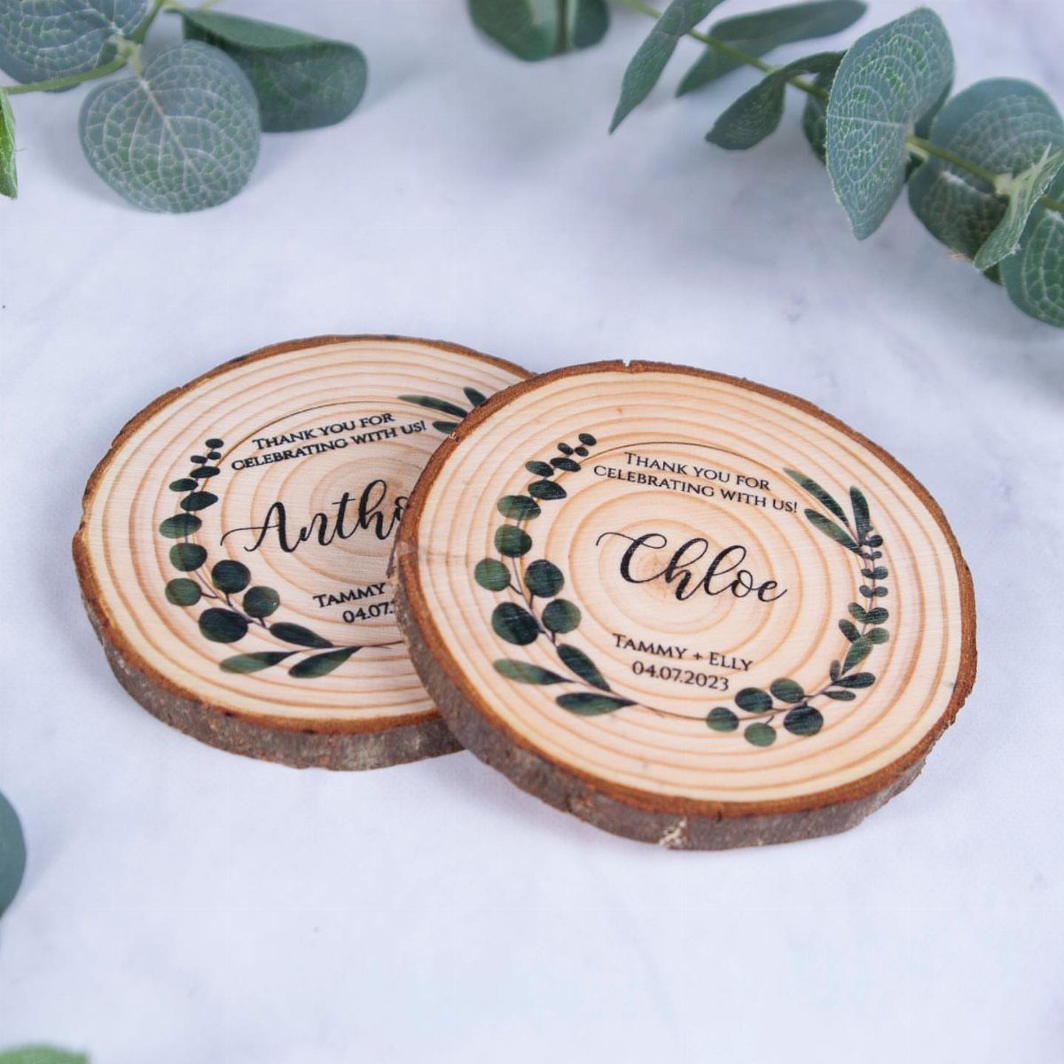 Two engraved wooden slices with names and leaves on a white background.
