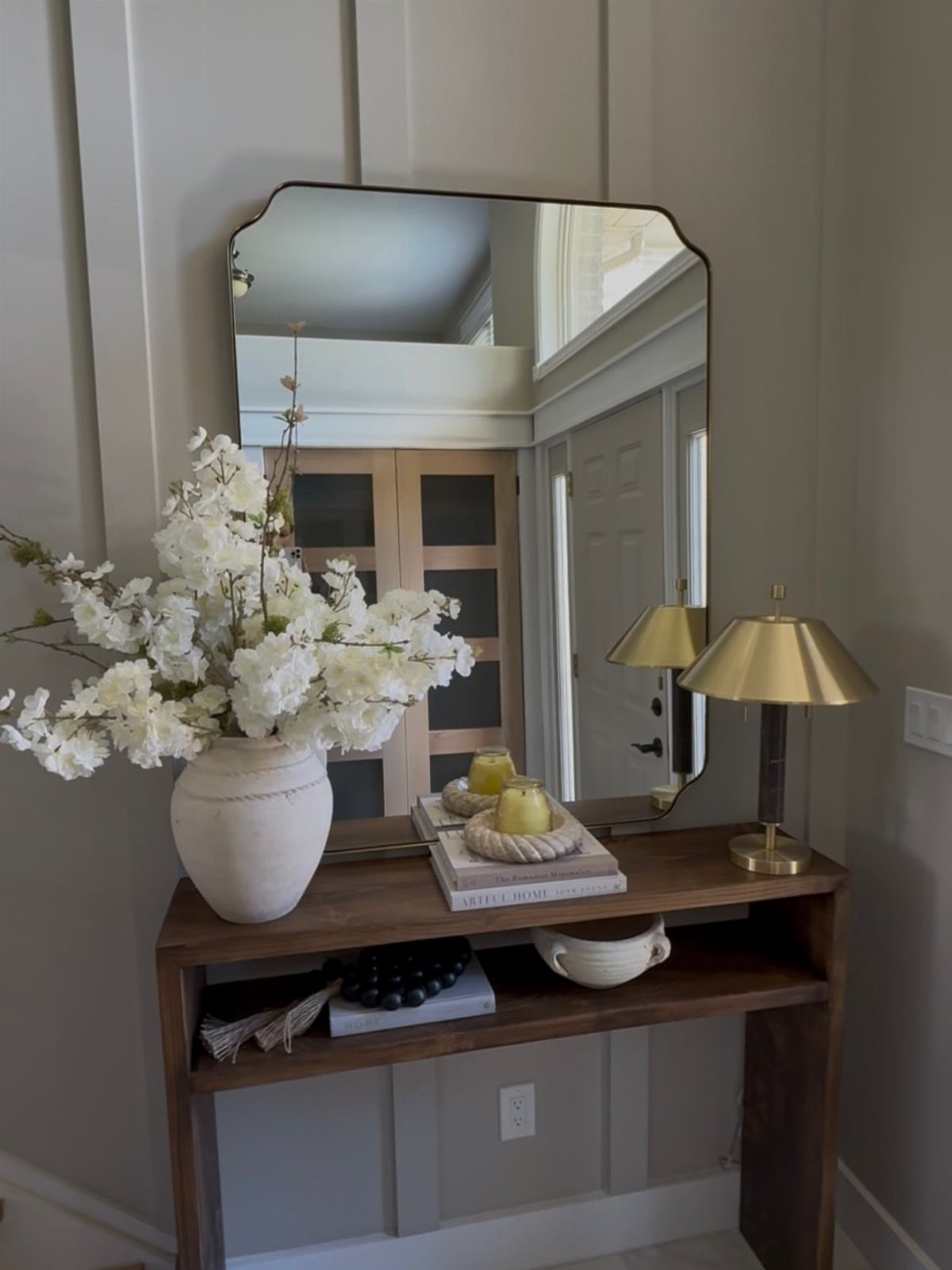 Mirror Wall Art: 25 Ideas from Sunburst to Floor Mirrors 4 Rectangular mirror with curved corners hanging above a wooden console table in an entryway.
