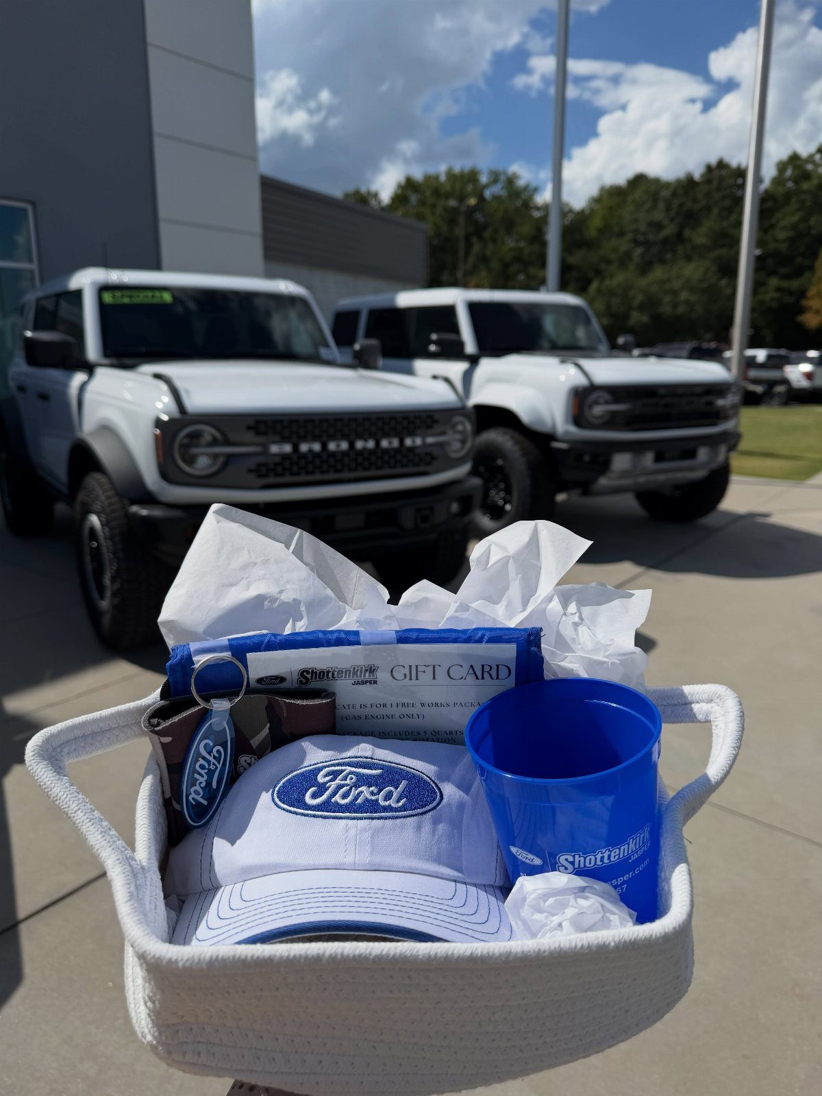 Ford branded gift basket with cap and cup in front of white Broncos.