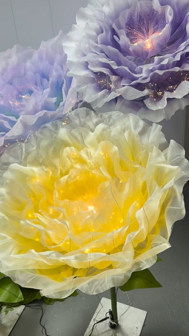Oversized artificial flowers in yellow and purple with internal glowing lights