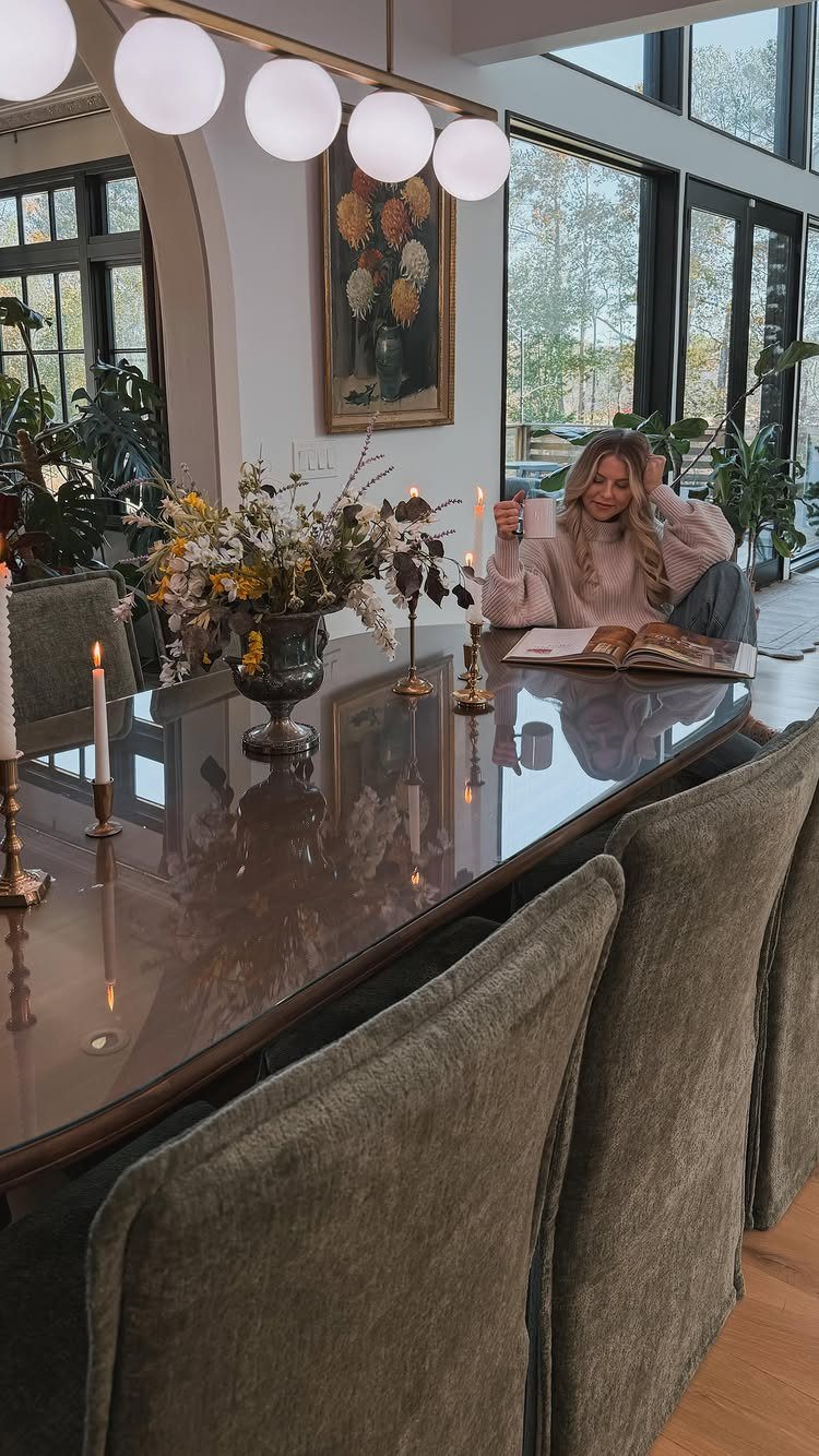 Olive green velvet dining chairs around a glossy dark brown table with globe lighting.