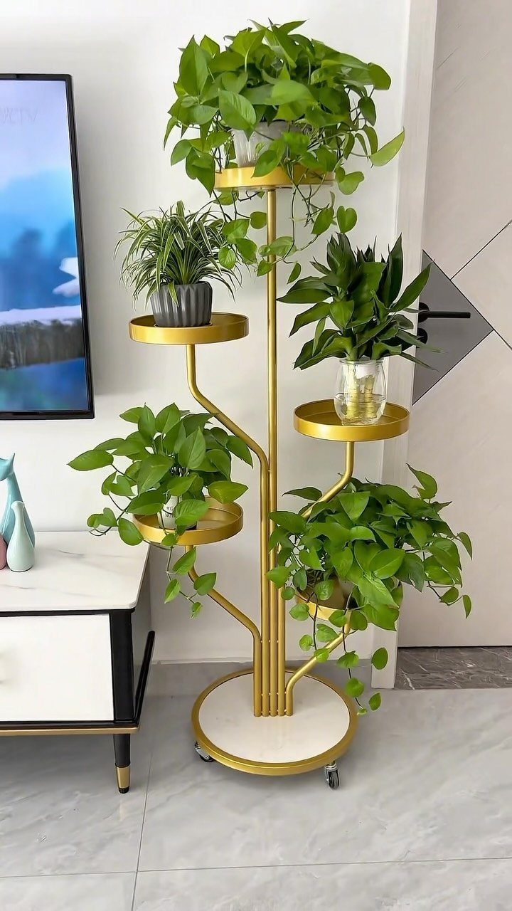 38 Flower Pot on Stand Ideas, from Iron Frames to Pedestals 12 Gold metal tiered plant stand with curved supports holding several green potted plants.