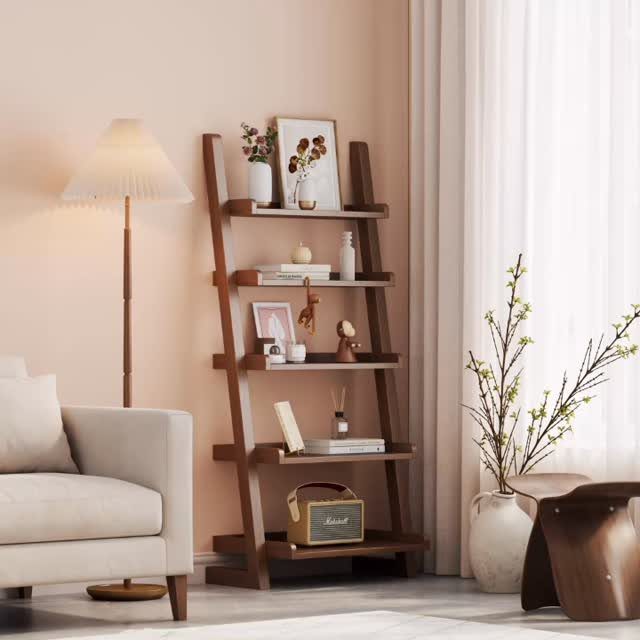 12 Ideas for Book Storage From Floating Shelves to Side Tables 9 Wooden ladder bookshelf leaning against a pink wall with books and decor items.