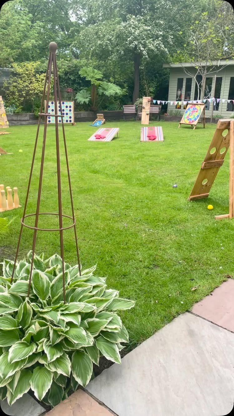 Various wooden lawn games set up on a green grassy backyard garden.