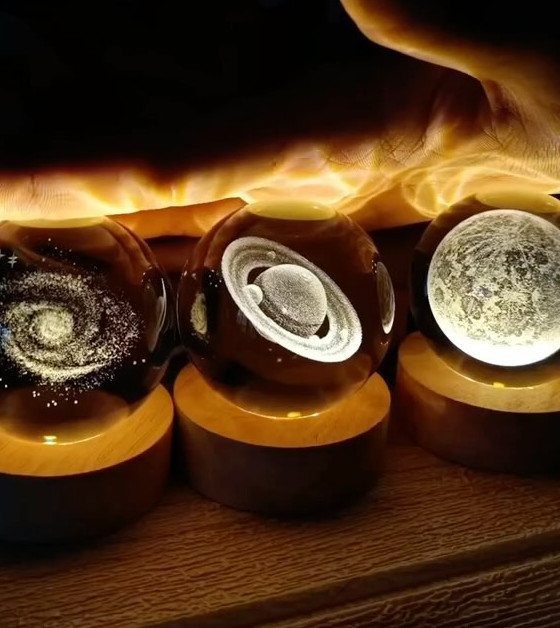 Three spherical glass lamps with celestial designs on circular wooden bases.