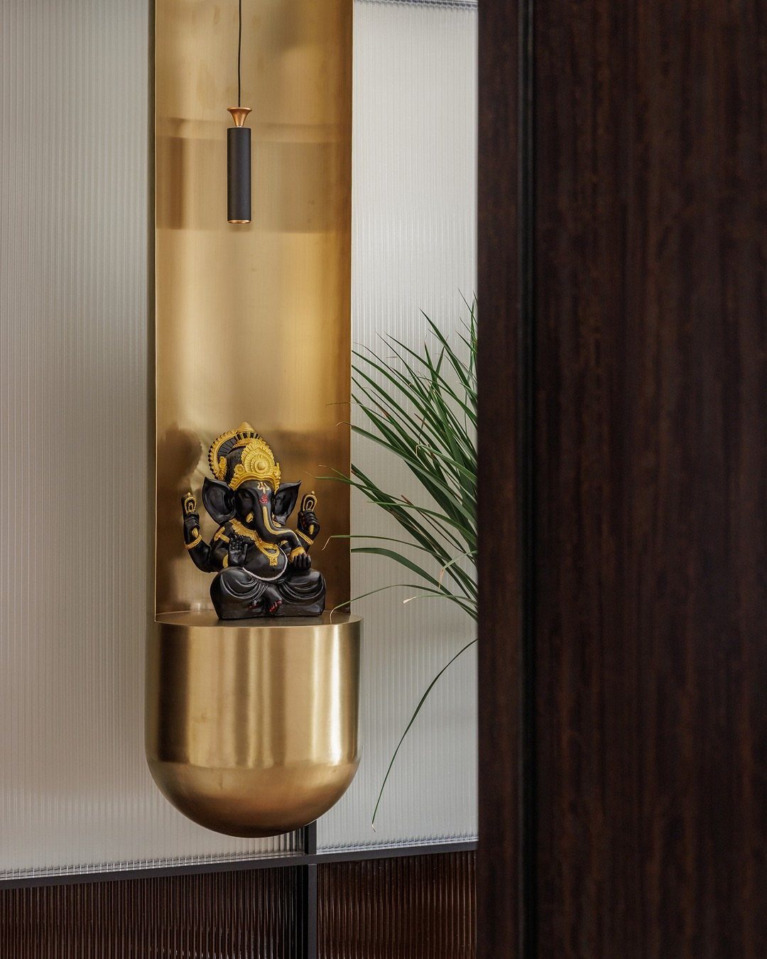 34 Puja Unit Design Modern Ideas for Your Home in 2026 20 Gold metallic wall niche with a black Ganesha idol and a pendant light.
