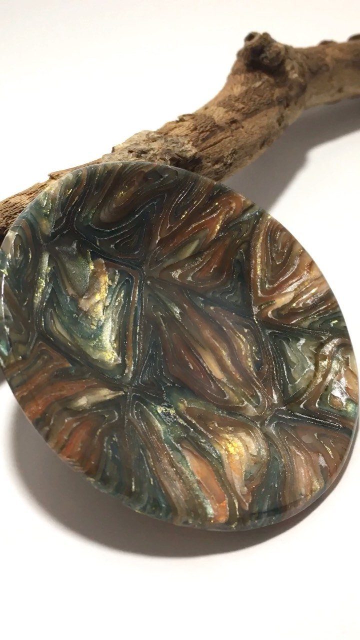 30 DIY Clay Crafts to Make with Air-Dry Clay for Home Decor 2 Marbled clay trinket dish with brown and gold swirls resting on a branch.