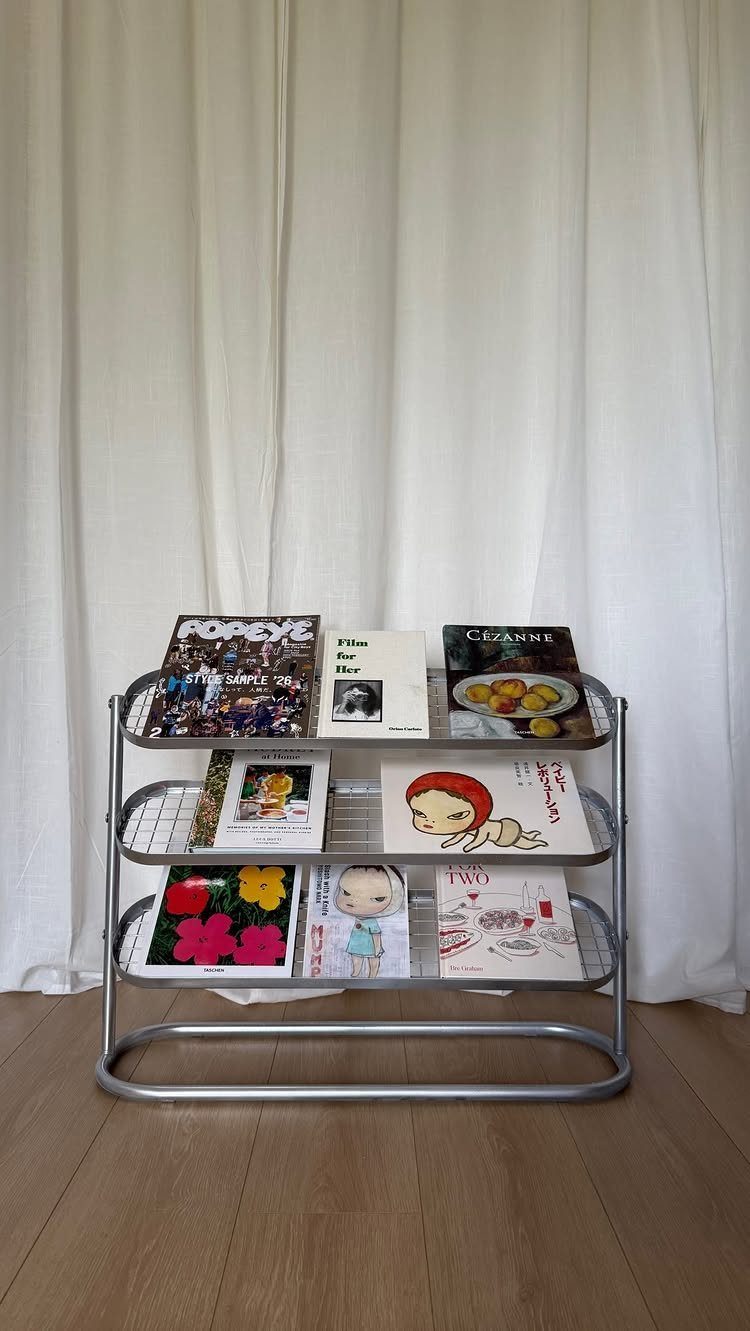 23 Cool House Items for Walls, Shelves, Desks, and Baths 20 Silver metal magazine rack with three shelves holding colorful magazines against white curtains.