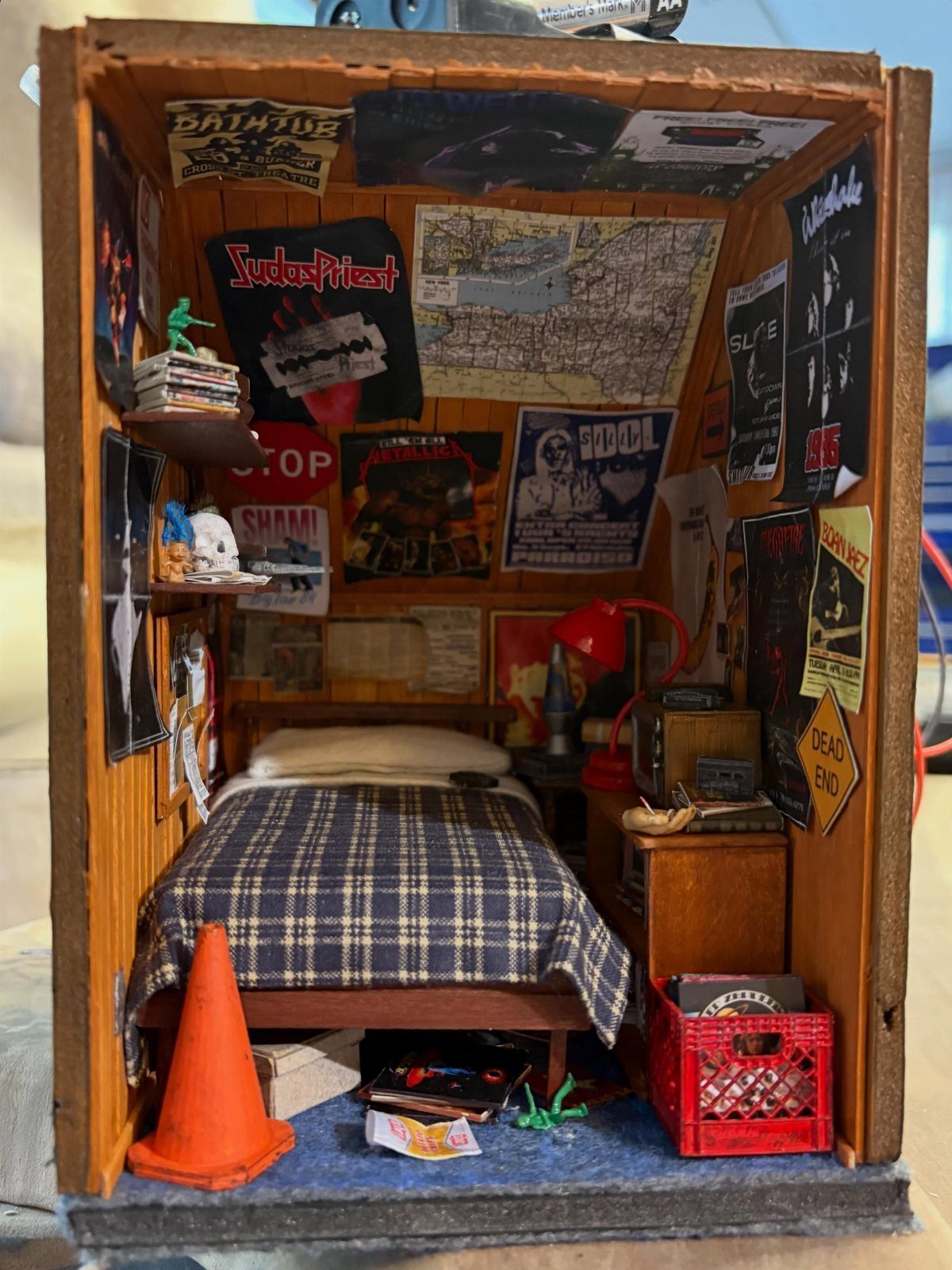 Miniature bedroom diorama inside a wooden box with posters and a small bed.