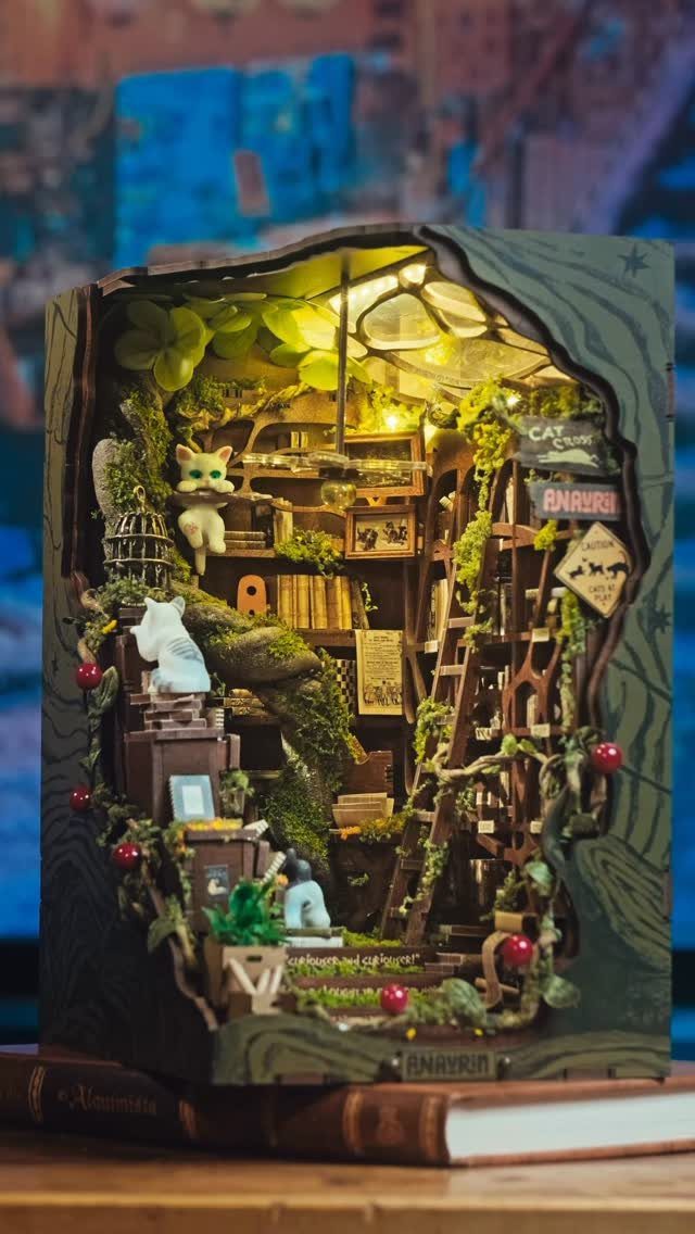 Miniature book nook kit with a tiny library, cats, and warm lighting.